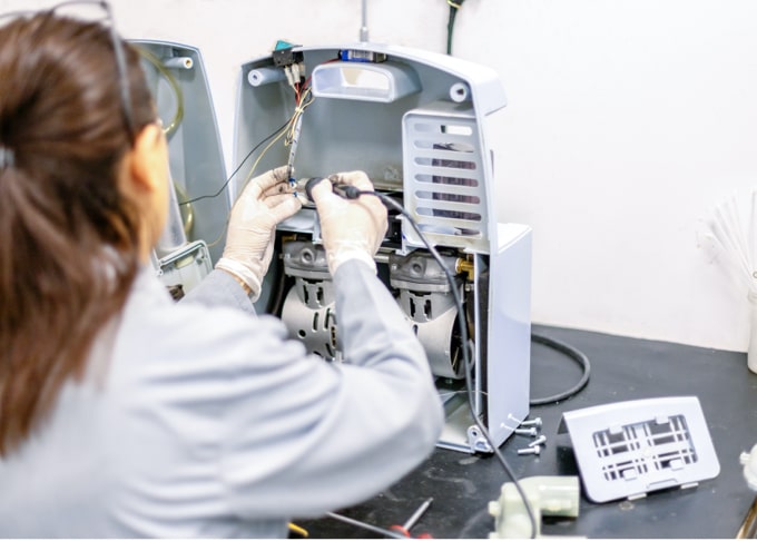 A medical equipment repairer repairing a machine.