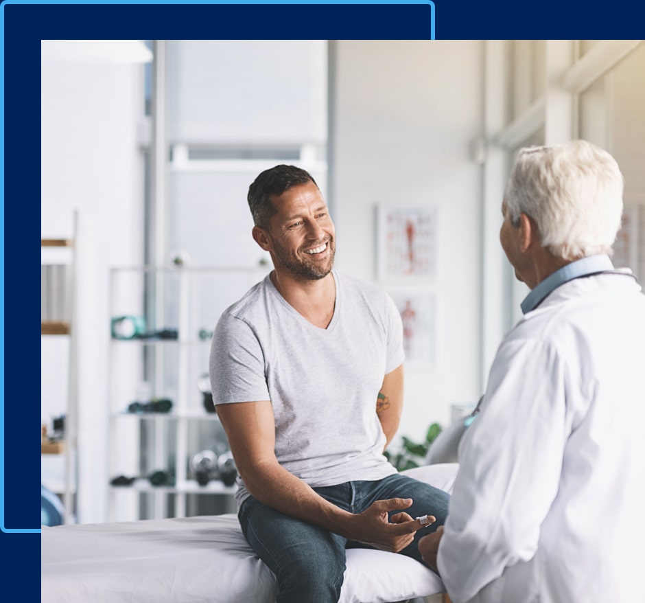 A white haired doctor talks to his smiling male patient.