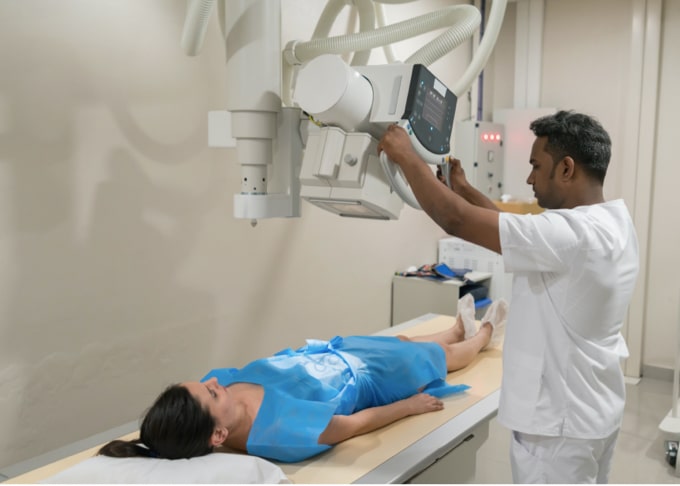 A Technician performing an X-ray on a patient's stomach.